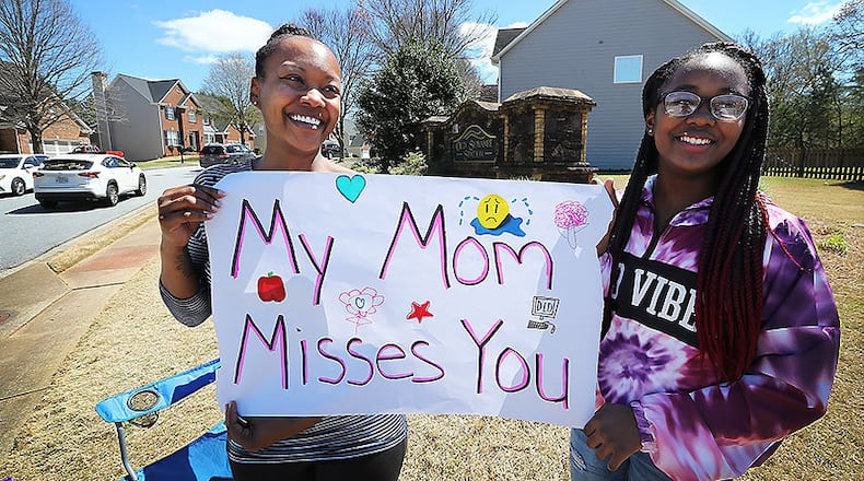 Amy Cole and her seventh-grade daughter Meghan, 12, turn out of their home in Old Suwanee Station to cheer on teachers from Roberts Elementary while they drive through nearly two dozen area neighborhoods on Wednesday, March 25, 2020, in Suwanee.