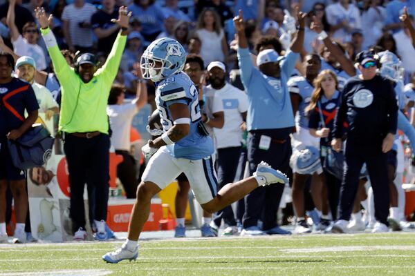 The bench celebrates as North Carolina defensive back Alijah Huzzie (28) evades the last Georgia Tech defender as he runs a punt back for a touchdown last year. (Chris Seward / AP)
