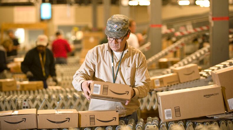 An Amazon.com employee grabs boxes off the conveyor belt to load in a truck at their Fernley, Nev., warehouse. Amazon started collecting sales tax from Georgians in September, 2013. (AP Photo/Scott Sady)