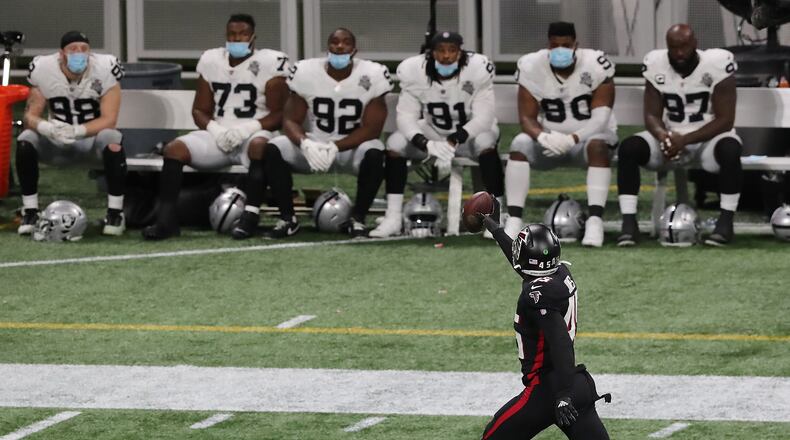 The Raiders bench looks on as Falcons linebacker Deion Jones intercepts a Derek Carr pass and returns it for a touchdown. (Curtis Compton / Curtis.Compton@ajc.com)