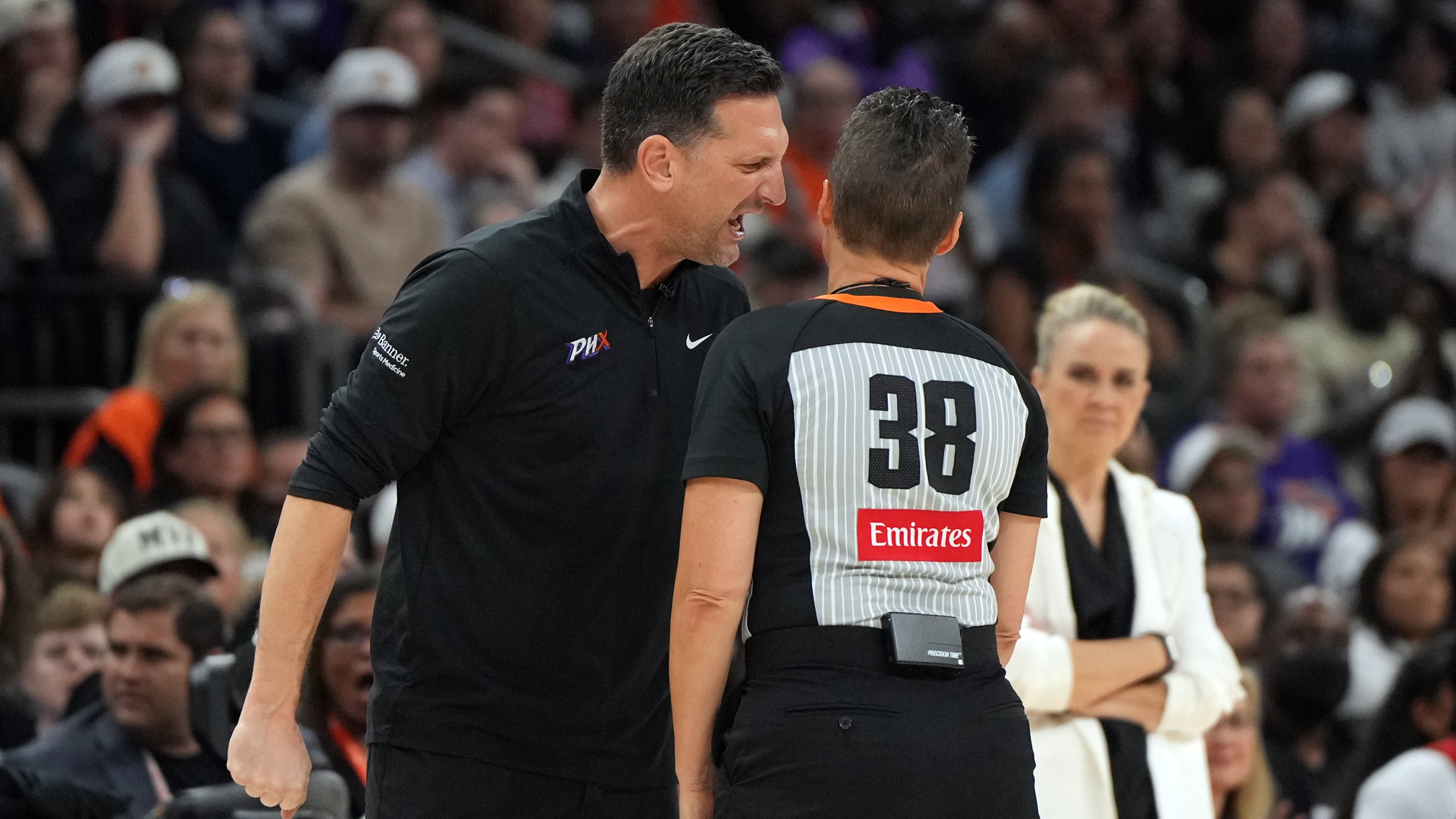 Phoenix Mercury head coach Nate Tibbetts, left, yells at official Lamont Simpson (38) after a foul during the second half of Game 4 of the WNBA basketball finals against the Las Vegas Aces, Friday, Oct. 10, 2025, in Phoenix. (AP Photo/Rick Scuteri)