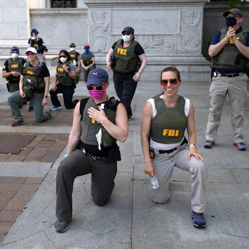 FILE - Federal Bureau of Investigation officers take a knee with demonstrators as they march on Pennsylvania Ave during a protest over the death of George Floyd on June 4, 2020, in Washington. (AP Photo/Jose Luis Magana, File)
