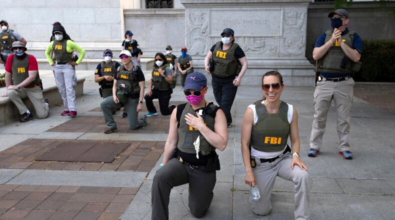FILE - Federal Bureau of Investigation officers take a knee with demonstrators as they march on Pennsylvania Ave during a protest over the death of George Floyd on June 4, 2020, in Washington. (AP Photo/Jose Luis Magana, File)