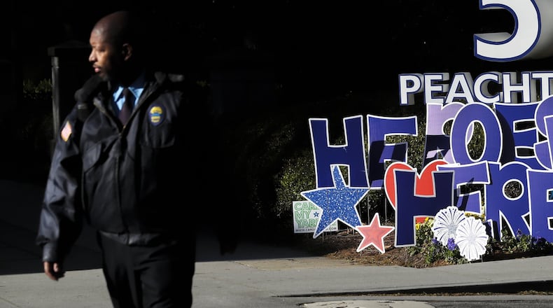 A security guard passes a sign saying, “Heroes Work Here” in front of Emory University Hospital Midtown at 550 Peachtree St NE in Atlanta on Thursday, April 2, 2020. JOHN SPINK/JSPINK@AJC.COM