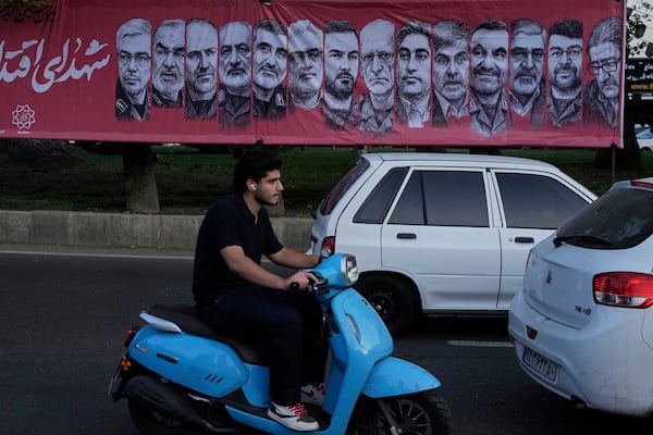 Vehicles drive past a banner showing portraits of the Iranian armed forces commanders and nuclear scientists who were killed in Israeli strike, at Tajrish Sq. in northern Tehran, Iran, Monday, June 30, 2025. (AP Phot/Vahid Salemi)