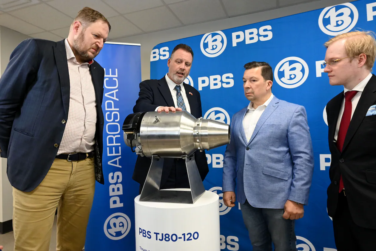 Erin Durham (second from left), CEO of PBS Aerospace, shows a PBS subsonic engine to (from left) David Müller, deputy minister of the Czech Ministry of Industry and Trade; Miloslav Stašek, Czech ambassador to the U.S.; and Jakub Fischer, managing director of PBS Aerospace on May 14, 2026, in Roswell. (Hyosub Shin/AJC)