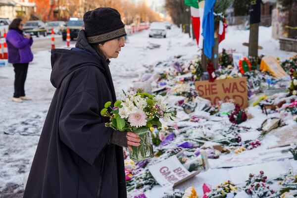 A woman lays flowers at the site where Renee Good was fatally shot by a federal immigration agent while she was in her vehicle last month in Minneapolis, Minn. (Ryan Murphy/The New York Times)