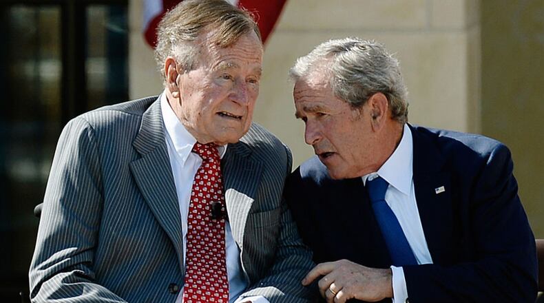 Former President George W. Bush (R) talks to his father President George H.W. Bush during the opening ceremony of the George W. Bush Presidential Center April 25, 2013 in Dallas, Texas. (Photo by Kevork Djansezian/Getty Images)