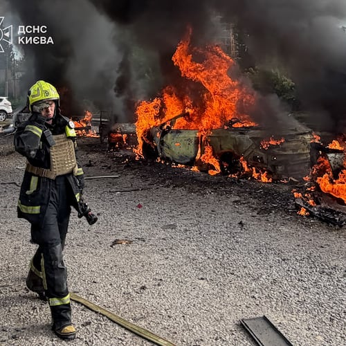 In this photo provided by the Ukrainian Emergency Service, a firefighters walk past burning cars as they work at the site, following a Russian air attack in Kyiv, Ukraine, Wednesday, Sept. 16, 2026. (Ukrainian Emergency Service via AP)