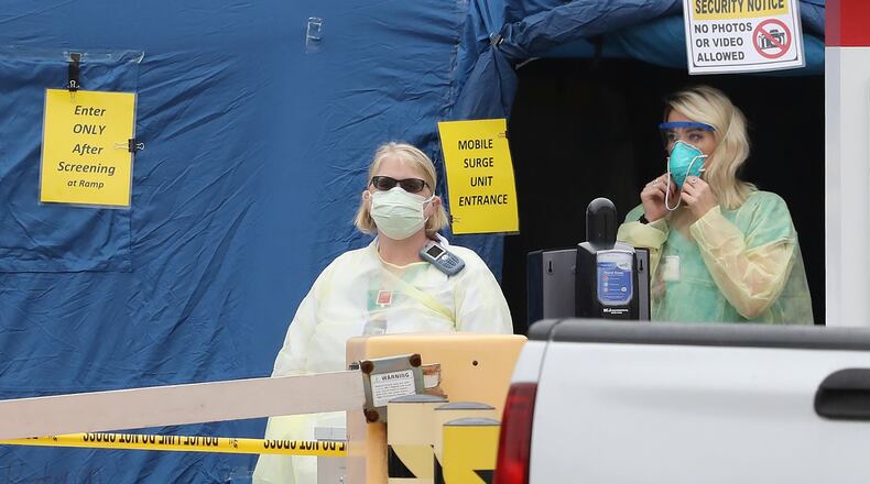 Medical workers at the entrance to the mobile surge unit tent for coronavirus testing outside the emergency entrance at WellStar Kennestone Hospital in Marietta on Tuesday, March 17. Curtis Compton ccompton@ajc.com