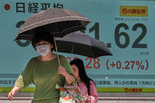 People walk in front of an electronic stock board showing Japan's Nikkei index at a securities firm Friday, June 20, 2025, in Tokyo. (AP Photo/Eugene Hoshiko)