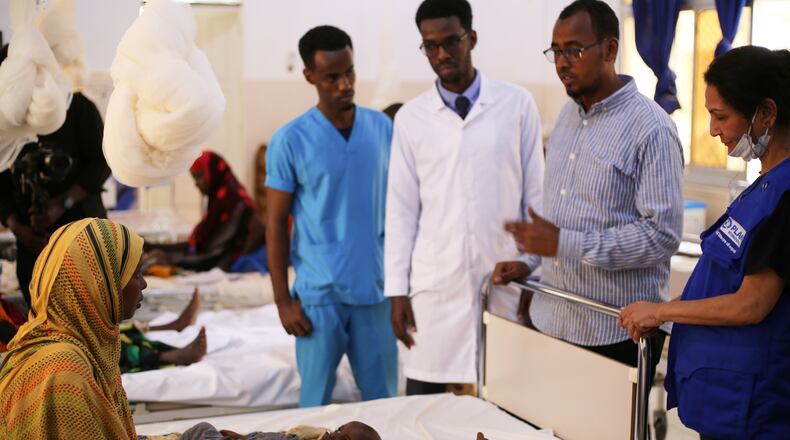 Health workers talk to a woman with her malnourished baby at Bay Hospital in Baidoa, Somalia, Tuesday, Aug. 4, 2026. (AP Photo/Mohamed Sheikh Nor)