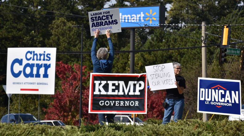 Stacey Abrams fans wave signs at a Towne Lake shopping mall in Cherokee County as GOP gubernatorial candidate Brian Kemp arrives with other statewide Republican candidates on Tuesday. HYOSUB SHIN / HSHIN@AJC.COM