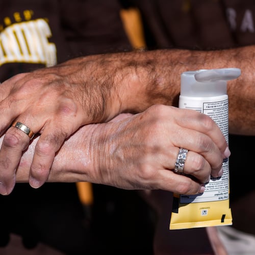 FILE - A man applies sunscreen to a woman's arm before a spring training baseball game between the San Diego Padres and the Chicago White Sox in Phoenix, Feb. 28, 2024. (AP Photo/Ashley Landis, File)