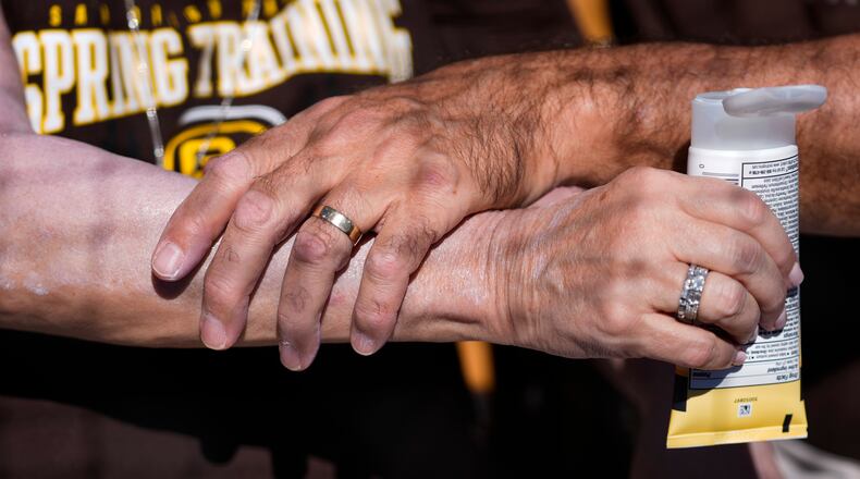 FILE - A man applies sunscreen to a woman's arm before a spring training baseball game between the San Diego Padres and the Chicago White Sox in Phoenix, Feb. 28, 2024. (AP Photo/Ashley Landis, File)