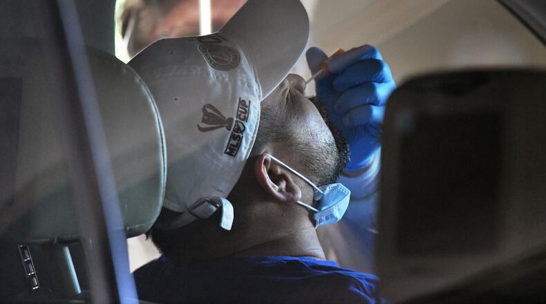 April 22, 2020 Duluth - A medical professional collects a nasal swab from a potential COVID-19 patient at a drive-through COVID-19 testing site for anyone who is experiencing symptoms at the Infinite Energy Center in Duluth on Wednesday, April 22, 2020. A drive-through COVID-19 testing center is open in Gwinnett County for anyone who is experiencing symptoms  â with no doctorâs orders necessary. The Gwinnett, Newton and Rockdale County Health Department conducted 800 tests at the event venue, its second large-scale testing event in a week. (Hyosub Shin / Hyosub.Shin@ajc.com)