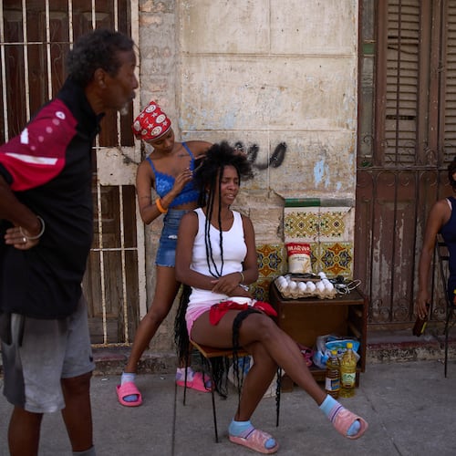 Hairdressers style the hair of their clients in the open air during a blackout in Havana, Cuba, Thursday, March 5, 2026. (AP Photo/Ramon Espinosa)