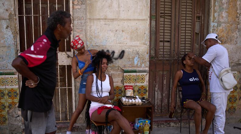Hairdressers style the hair of their clients in the open air during a blackout in Havana, Cuba, Thursday, March 5, 2026. (AP Photo/Ramon Espinosa)