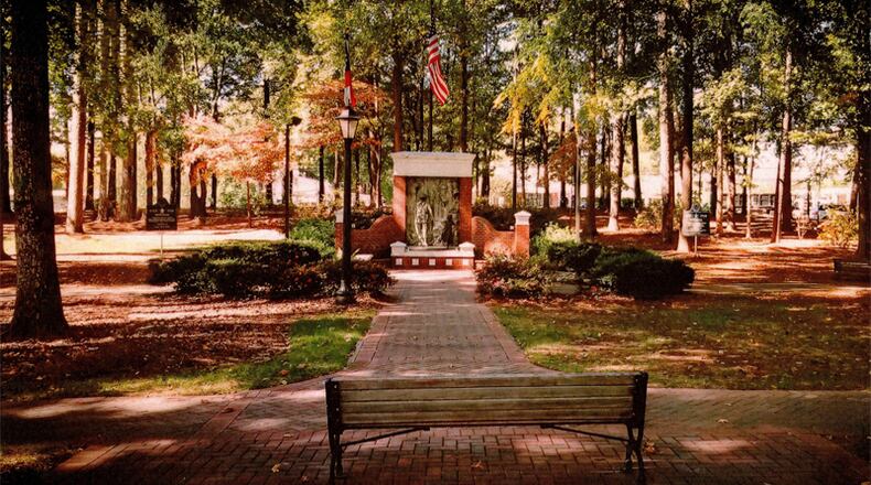 Photo illustration depicts memorials to armed forces service members and their families on either side of the Faces of War Memorial on the grounds of Roswell City Hall. CITY OF ROSWELL