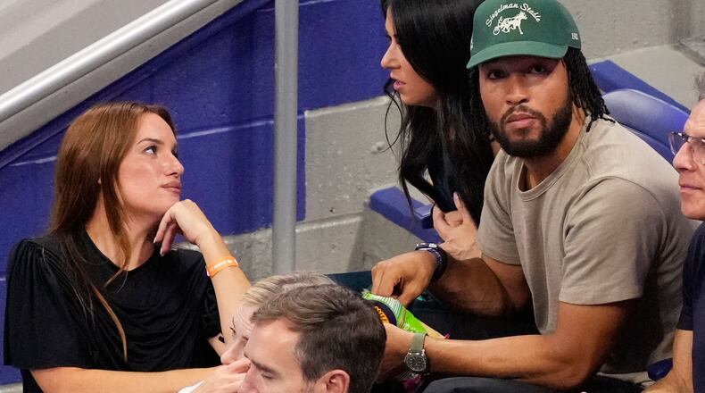 Hannah Berner, left, speaks with Ali Brunson as New York Knicks' Jalen Brunson sits next to her at a match between Ben Shelton, of the United States, and Frances Tiafoe, of the United States, during the men's singles semifinals of the U.S. Open tennis championships Friday, Sept. 11, 2026, in New York. (AP Photo/Yuki Iwamura)