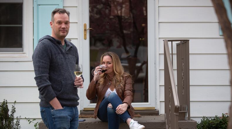 Ian Woolard and Leigh Anne Rehkopf sit on the front porch of Rehkopf's Smyrna home. The couple's first date in August was a socially distanced, and dressed-down, get together in Rehkopf's carport. (STEVE SCHAEFER FOR THE ATLANTA JOURNAL-CONSTITUTION)