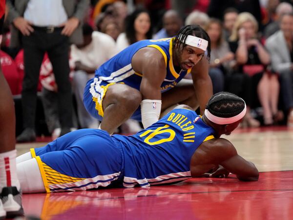 Golden State Warriors guard Buddy Hield (7) checks on forward Jimmy Butler III (10) after a collision with Houston Rockets' Amen Thompson under the basket during the first half of Game 2 of an NBA basketball first-round playoff series against the Houston Rockets in Houston, Wednesday, April 23, 2025. (AP Photo/Karen Warren)