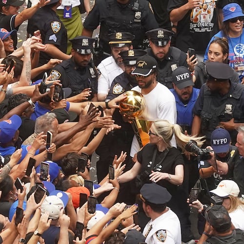 Jalen Brunson, upper right, of the NBA Champion New York Knicks carries the trophy for fans during the ticker-tape parade on Broadway, in New York's "Canyon of Heroes," Thursday, June 18, 2026. (AP Photo/Richard Drew)