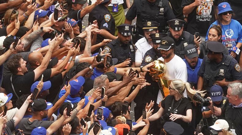 Jalen Brunson, upper right, of the NBA Champion New York Knicks carries the trophy for fans during the ticker-tape parade on Broadway, in New York's "Canyon of Heroes," Thursday, June 18, 2026. (AP Photo/Richard Drew)