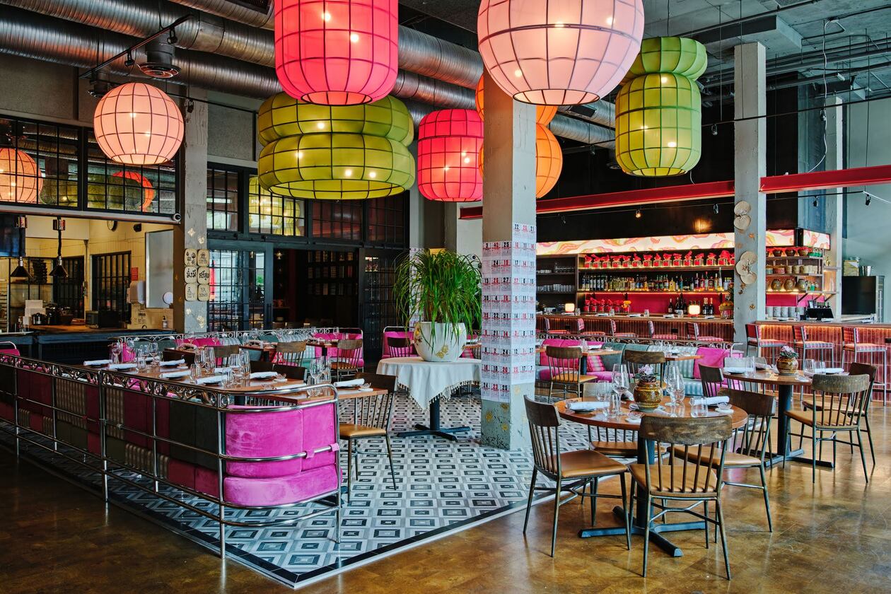 The empty interior of Pink Lotus. Notably, it has bright, colorful festive pendant lights resembling Chinese lanterns hanging from the ceiling, and chairs upholstered in bright pink.