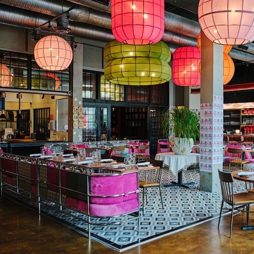 The empty interior of Pink Lotus. Notably, it has bright, colorful festive pendant lights resembling Chinese lanterns hanging from the ceiling, and chairs upholstered in bright pink.