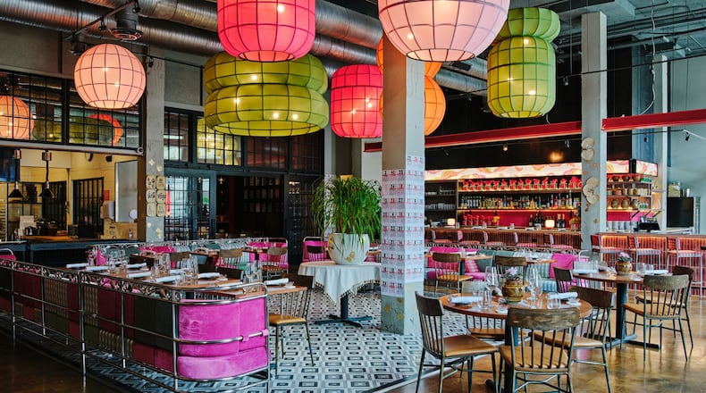 The empty interior of Pink Lotus. Notably, it has bright, colorful festive pendant lights resembling Chinese lanterns hanging from the ceiling, and chairs upholstered in bright pink.