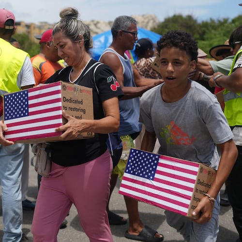 People affected by the earthquakes carry U.S. humanitarian aid after receiving it in La Guaira, Venezuela, Wednesday, July 8, 2026. (AP Photo/Ariana Cubillos)