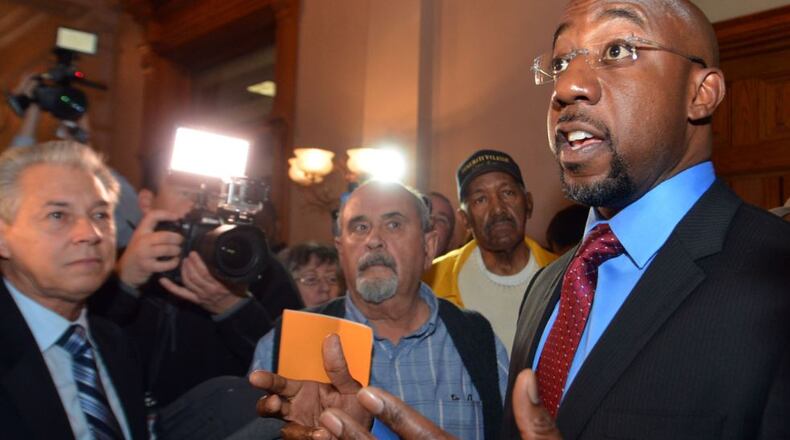 The Rev Raphael Warnock, pastor of Ebenezer Baptist Church, gives remarks before staging a sit in with other protestors in front of the governor's office in 2014. Kent D. Johnson, kdjohnson@ajc.com