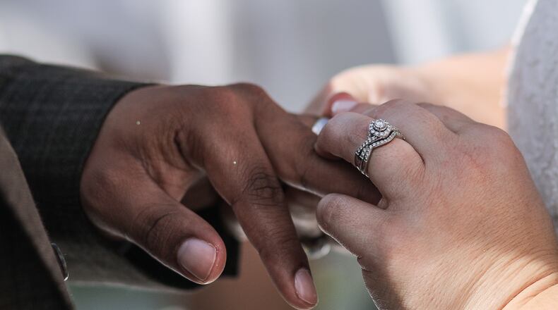 File Photo: A bride slides a ring onto the finger of her groom. Damon Higgins / The Palm Beach Post
