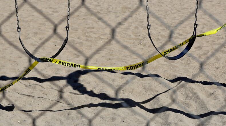 A temporary chain link fence keeps people off a swing set at a park Friday, April 3, 2020, in Tempe, Arizona, because of the COVID-19 pandemic. (AP Photo/Matt York)