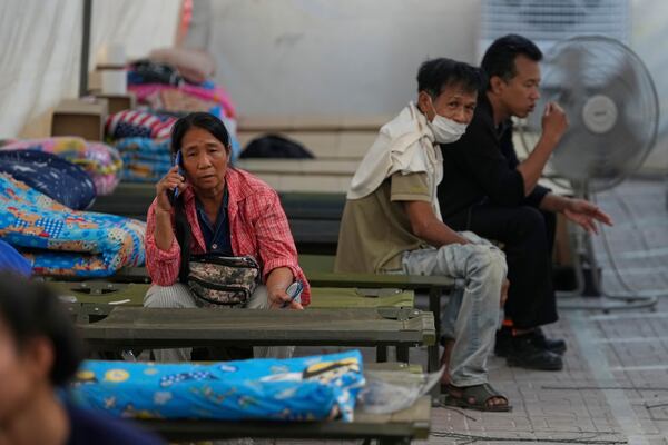 Buaban Konkham, 55, left, talks on her mobile as she waits for news of her son, who is missing after an under-construction high-rise building collapsed in an earthquake in Bangkok, Thailand, Monday, March, 31, 2025. (AP Photo/Manish Swarup)