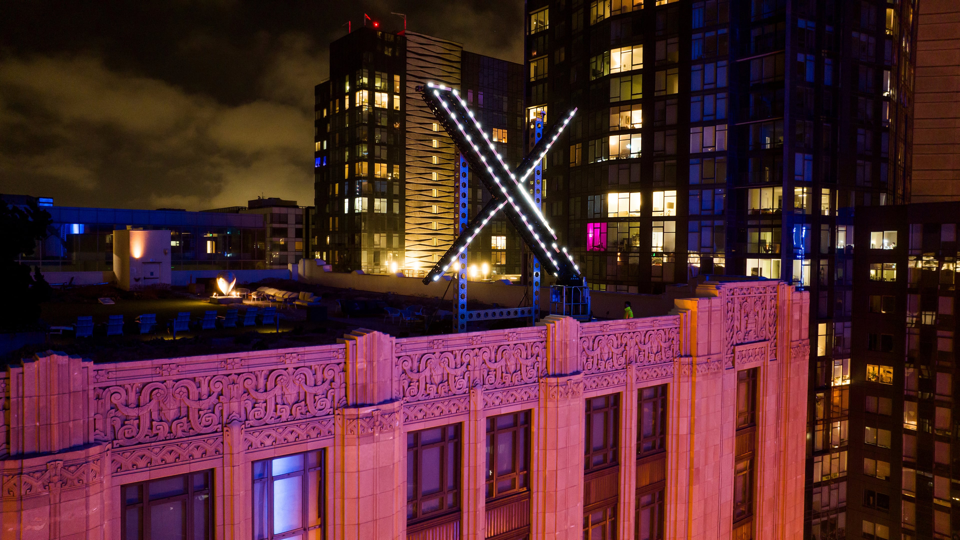 FILE - Workers install lighting on an "X" sign atop the company headquarters in downtown San Francisco, July 28, 2023. (AP Photo/Noah Berger, File)
