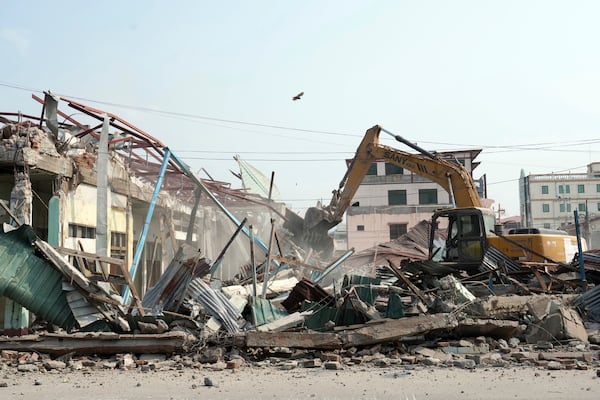 A volunteer drives a backhoe to clear debris of a building at a market, after one month of the strong earthquake in Naypyitaw, Myanmar, Monday, April 28, 2025. (AP Photo/Aung Shine Oo)