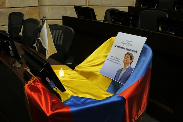 A picture of Colombian Senator Miguel Uribe Turbay and a Colombian flag cover his seat at Congress while he is in critical condition after being shot at a political rally in Bogota, Colombia, Monday, June 9, 2025. (AP Photo/Ivan Valencia)