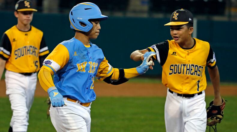Hawaii's Aukai Kea (left) is greeted by Peachtree City's Tai Peete (7) as he rounds third after hitting a walk off, two-run home run in the eleventh inning of the Little League World Series tournament  Friday, Aug. 17, 2018, in South Williamsport, Pa.