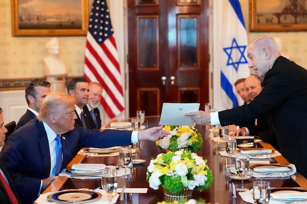 Israel's Prime Minister Benjamin Netanyahu, right, hands President Donald Trump a folder during a meeting in the Blue Room of the White House, Monday, July 7, 2025, in Washington. (AP Photo/Alex Brandon)