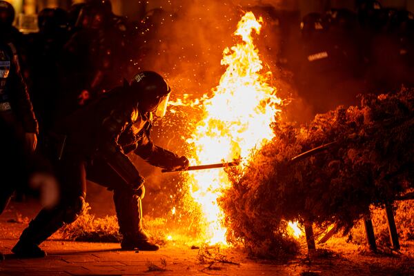 FILE- A riot policeman attempts to extinguish a fire as supporters of Calin Georgescu protested the electoral body's decision to reject his candidacy in a presidential election redo in Bucharest, Romania, Sunday, March 9, 2025. (AP Photo/Vadim Ghirda, File)
