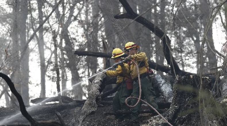 Firefighters Valarie Lopez (left) and Mark Tabaez work to cool hot spots on a hillside in Clayton. (Credit: Associated Press)