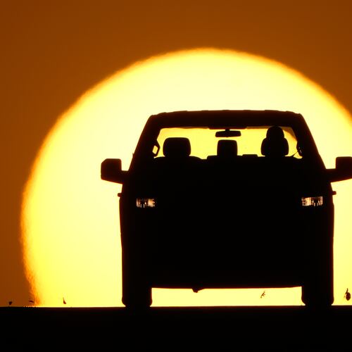 FILE - A motorist is silhouetted by the setting sun March 26, 2026, in Lenexa, Kan. (AP Photo/Charlie Riedel)