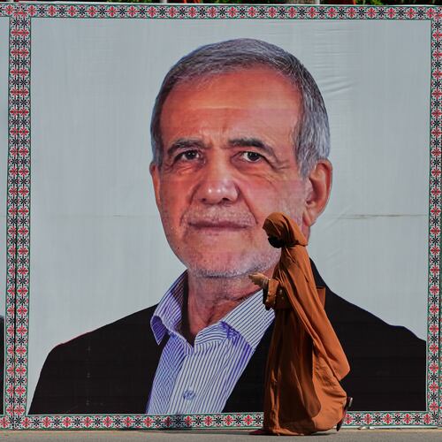 A woman walks past a welcoming billboard featuring Iranian President Masoud Pezeshkian along a roadside in Islamabad, Pakistan, Tuesday, June 23, 2026. (AP Photo/Anjum Naveed)
