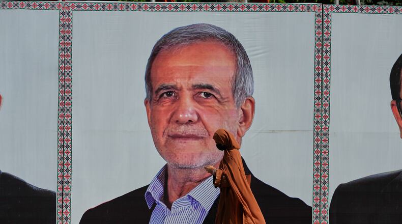 A woman walks past a welcoming billboard featuring Iranian President Masoud Pezeshkian along a roadside in Islamabad, Pakistan, Tuesday, June 23, 2026. (AP Photo/Anjum Naveed)