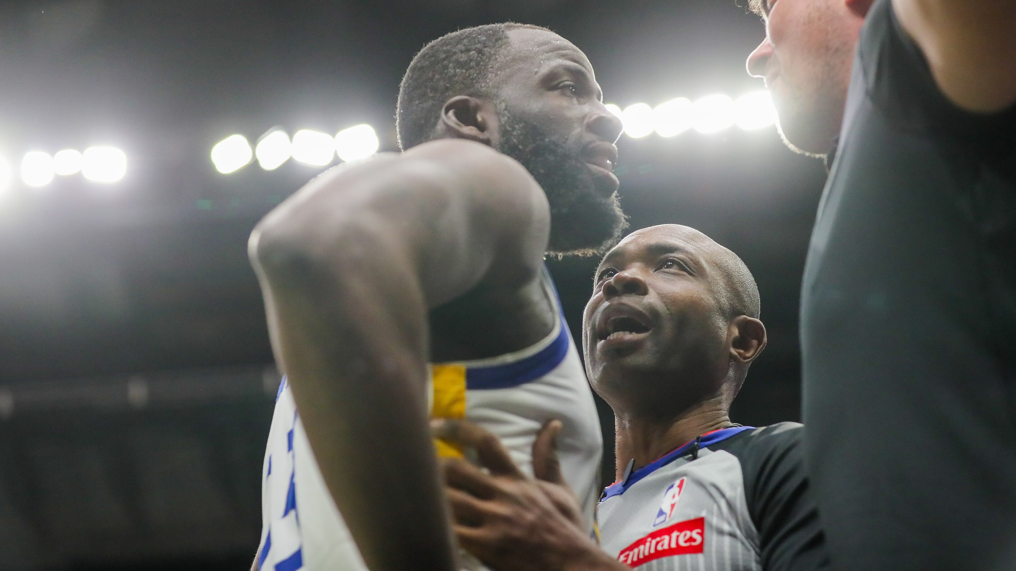 Golden State Warriors forward Draymond Green (23) is held back by referee Courtney Kirkland while talking to New Orleans Pelicans fan Sam Green during the first half of an NBA basketball game against the New Orleans Pelicans in New Orleans, Sunday, Nov. 16, 2025. (David Grunfeld/The Times-Picayune via AP)