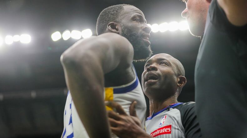 Golden State Warriors forward Draymond Green (23) is held back by referee Courtney Kirkland while talking to New Orleans Pelicans fan Sam Green during the first half of an NBA basketball game against the New Orleans Pelicans in New Orleans, Sunday, Nov. 16, 2025. (David Grunfeld/The Times-Picayune via AP)