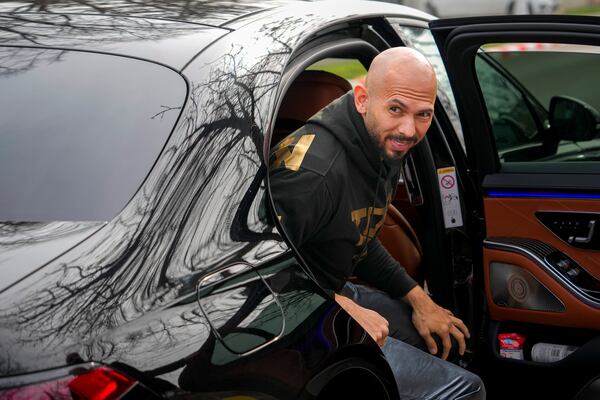 Andrew Tate arrives at a police station to checking in as part of his judicial control, which requires him to appear before judicial authorities in Romania when summoned, after returning from the United States, in Voluntari, Romania, Monday, March 24, 2025. (AP Photo/Vadim Ghirda)