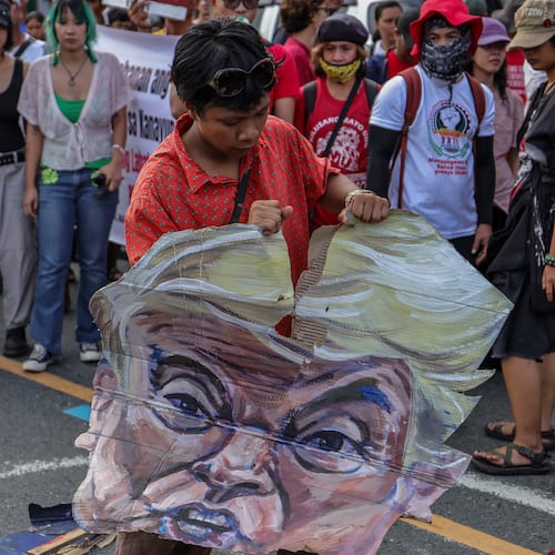 A protester destroys an effigy of U.S. President Donald Trump during a protest march in Quezon City, Philippines Monday, July 27, 2026, ahead of the State of the Nation Address by President Marcos Jr. (AP Photo/Gerard Carreon)